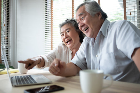 Senior Asian couple having fun while looking at the computer screen.