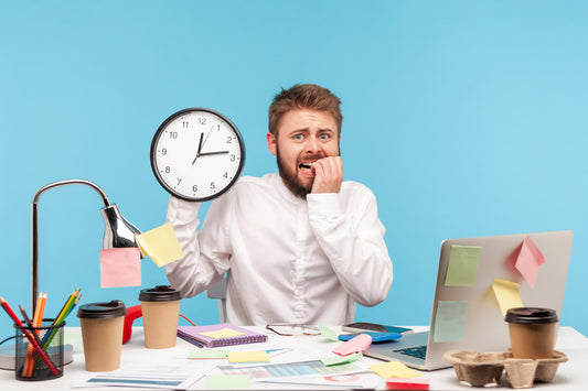 Man in a white shirt holding a clock while anxiously biting his nails